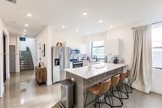a kitchen with stainless steel appliances kitchen island granite countertop a refrigerator and a sink