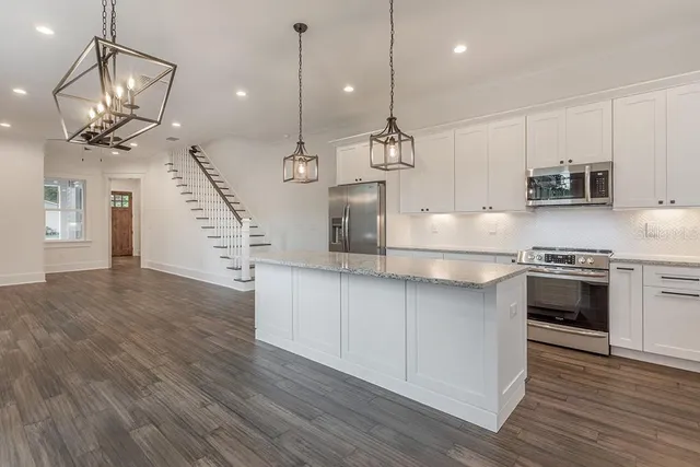 a kitchen with stainless steel appliances granite countertop a sink a stove and a wooden floors