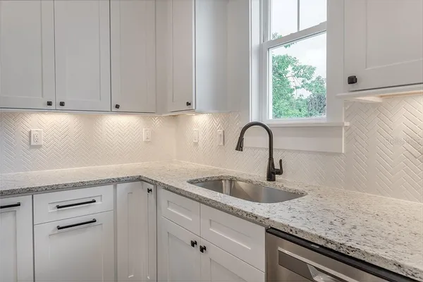 a kitchen with granite countertop white cabinets and a sink