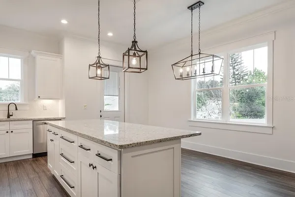 a kitchen with kitchen island granite countertop a sink a window appliances and cabinets