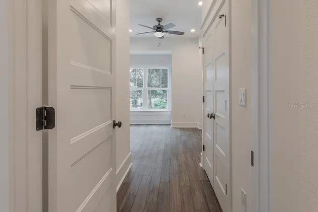 a view of a hallway with wooden floor and cabinet