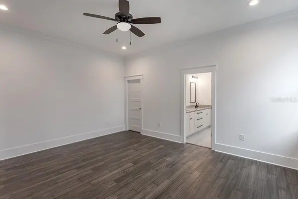 an empty room with wooden floor fan and windows