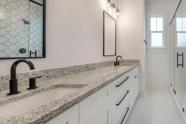 a bathroom with a granite countertop sink a mirror and shower