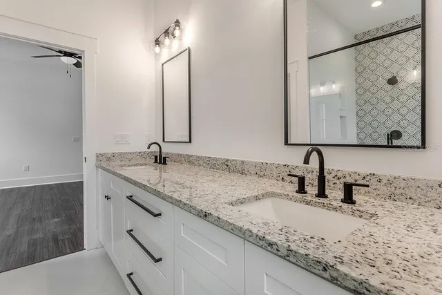 a bathroom with a granite countertop sink a mirror and shower