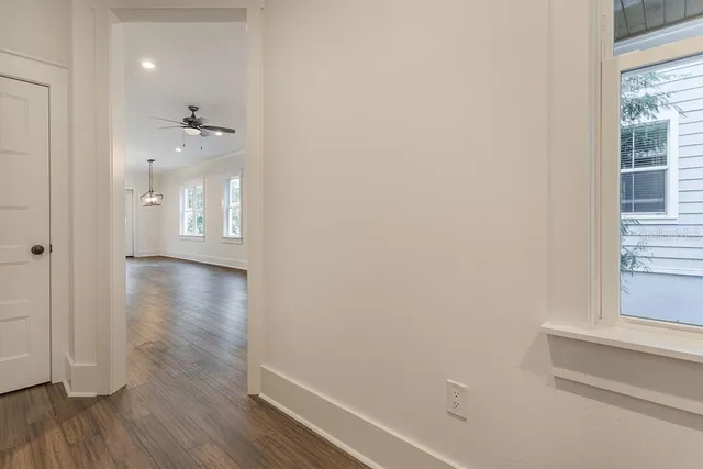 a view of a hallway with wooden floor and a bathroom