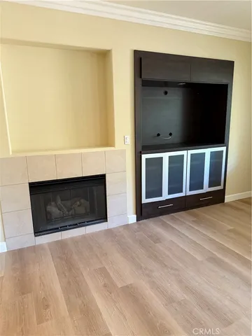 a view of an empty room with wooden floor and a fireplace