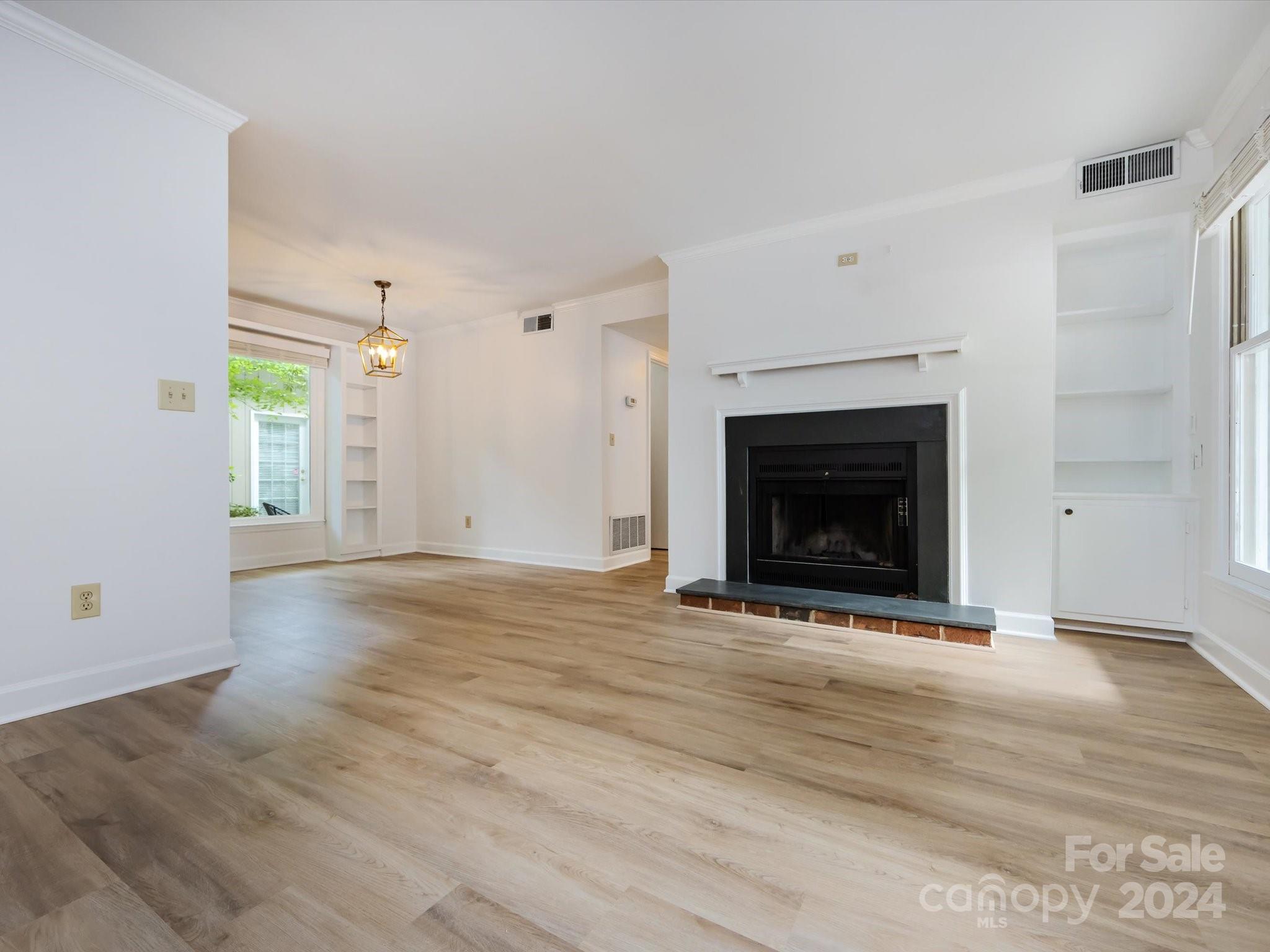 430 Queens Road, Unit 112 Charlotte, NC 28207 - Photo 4 of 19 a view of an empty room with wooden floor fireplace and a window