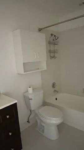 a white toilet sitting next to a bathroom sink and vanity