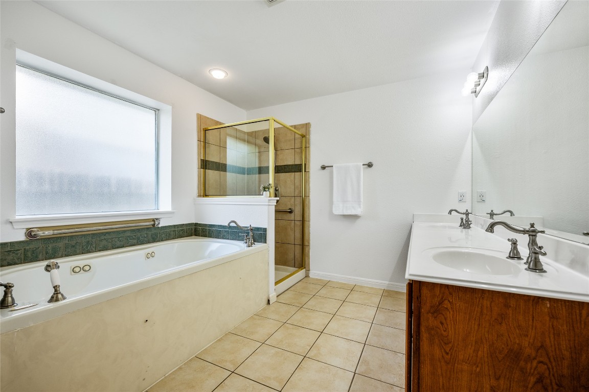 1564 Lorson Loop Round Rock, TX 78665 - Photo 14 of 27 Full bath with light tile patterned floors, a garden tub, double vanity, and a stall shower