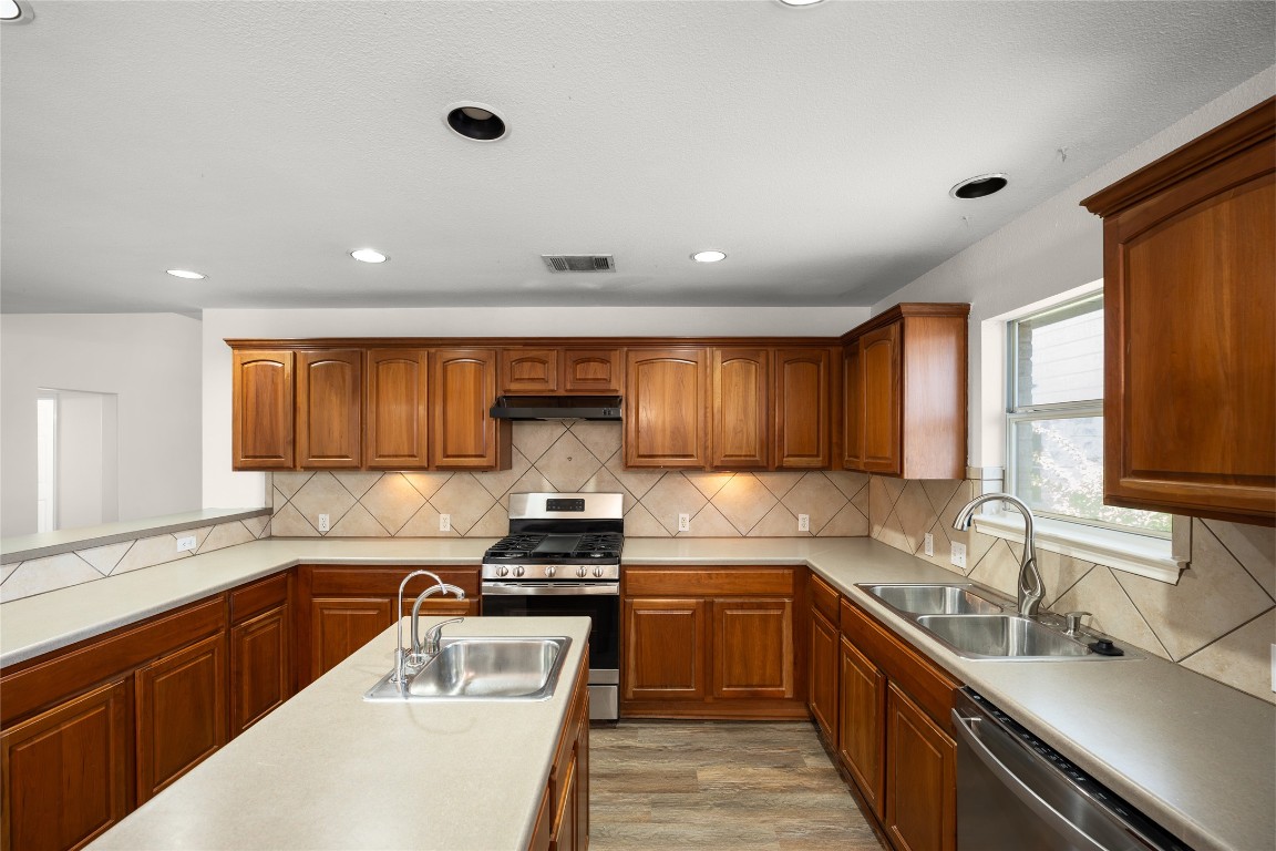 1564 Lorson Loop Round Rock, TX 78665 - Photo 7 of 27 Kitchen featuring brown cabinets, appliances with stainless steel finishes, decorative backsplash, light countertops, and recessed lighting
