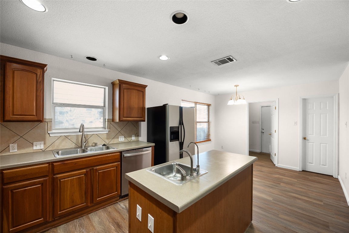 1564 Lorson Loop Round Rock, TX 78665 - Photo 9 of 27 Kitchen featuring dark wood finished floors, light countertops, decorative backsplash, a kitchen island with sink, and recessed lighting