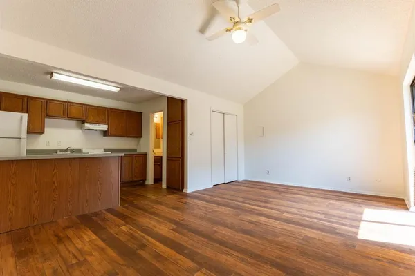 a view of kitchen and empty room with wooden floor