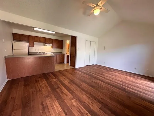a view of kitchen and empty room with wooden floor