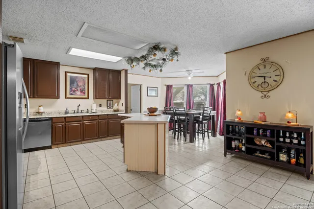 a kitchen with stainless steel appliances kitchen island granite countertop a refrigerator a stove a sink and a dining table with wooden floor