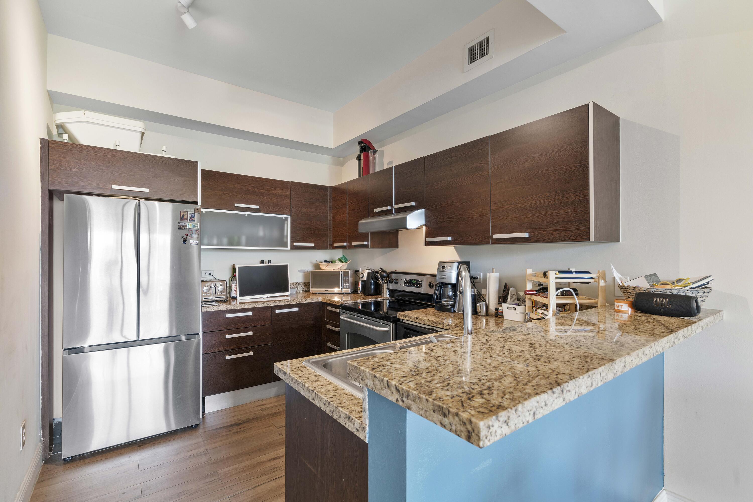 2525 Southwest 3rd Avenue, Unit 807 Miami, FL 33129 - Photo 18 of 27 a kitchen with kitchen island granite countertop a sink refrigerator and microwave