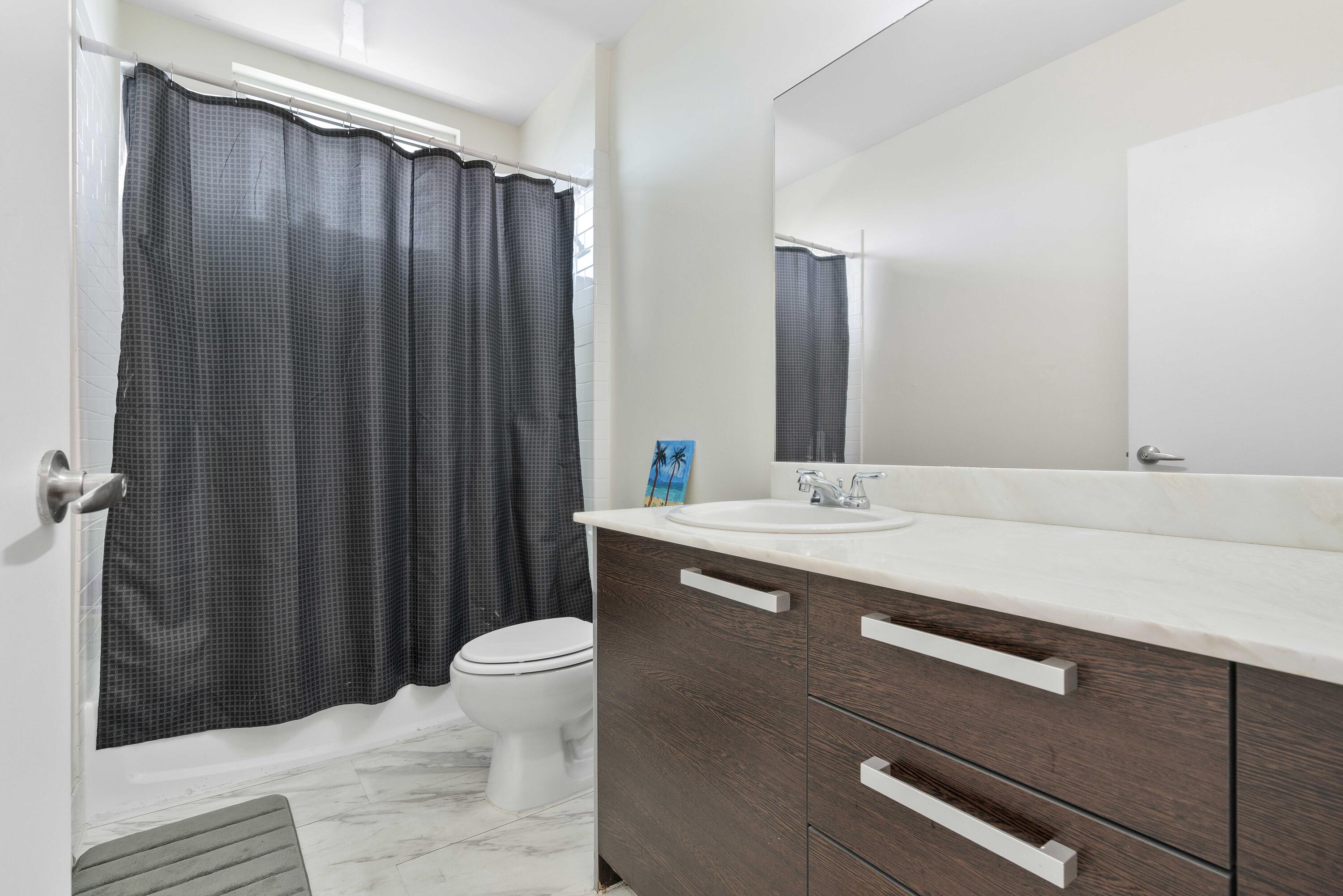 2525 Southwest 3rd Avenue, Unit 807 Miami, FL 33129 - Photo 25 of 27 a bathroom with a sink a toilet a mirror and shower curtain