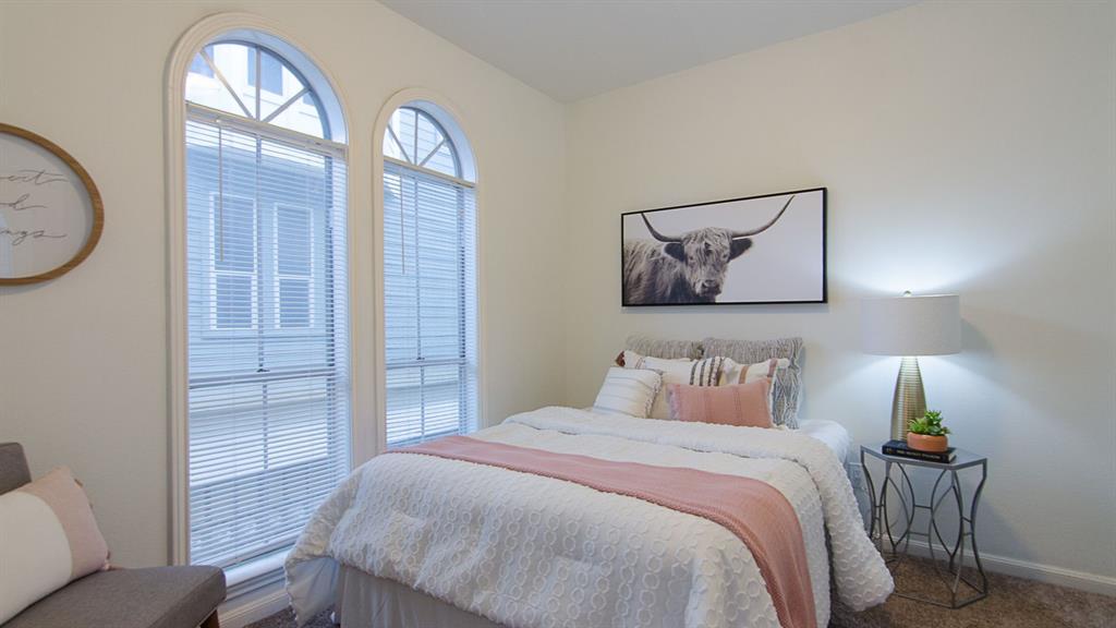 2529 Rio Grande Street, Unit 39 Austin, TX 78705 - Photo 8 of 21 Arched windows invite natural light to illuminate the cozy bedroom finished with soft carpet flooring.