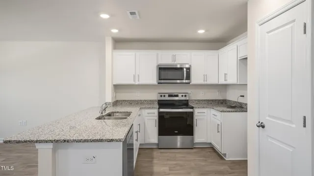 a kitchen with granite countertop a stove sink and microwave