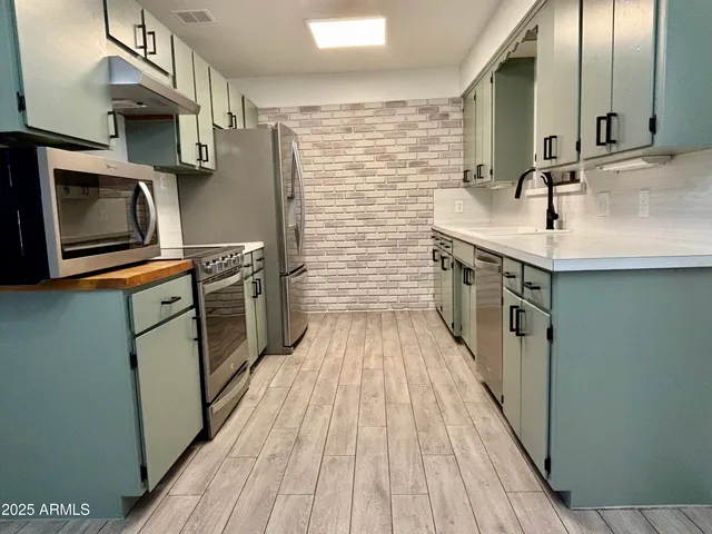 a kitchen with stainless steel appliances granite countertop a sink stove and refrigerator