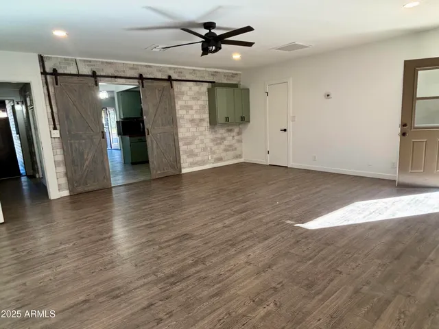 a view of a livingroom with wooden floor a ceiling fan and staircase