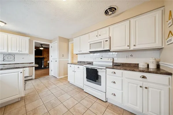 a kitchen with granite countertop white cabinets and white appliances