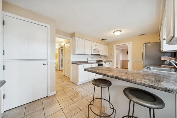 a kitchen with stainless steel appliances granite countertop a refrigerator a sink a stove a dining table and chairs