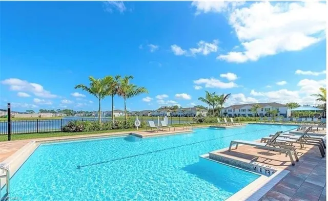 a view of a swimming pool with lawn chairs and plants