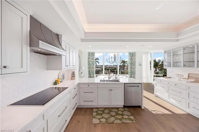 a large white kitchen with a window a sink and cabinets
