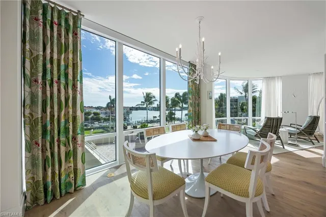a dining room with furniture large windows and wooden floor