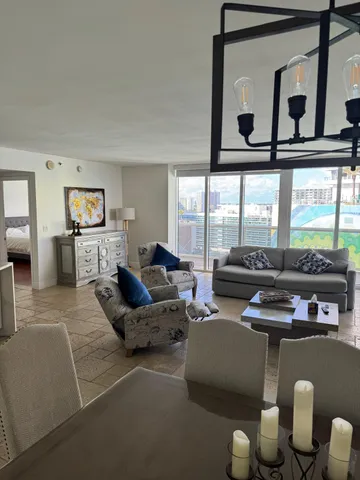 a living room with furniture a flat screen tv and a floor to ceiling window