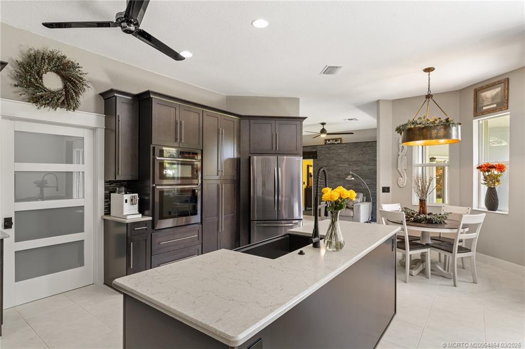 2072 Southeast Hanford Road Port St. Lucie, FL 34952 - Photo 11 of 58 a kitchen with stainless steel appliances kitchen island granite countertop a refrigerator a stove and a dining table with wooden floor
