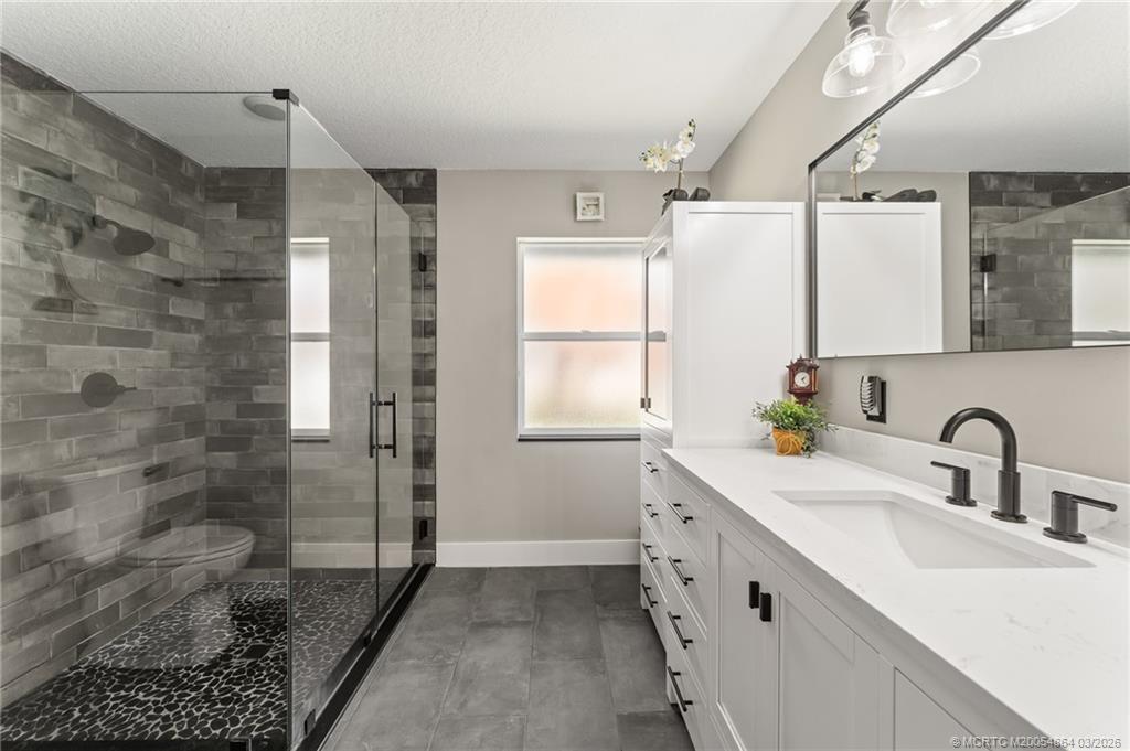 2072 Southeast Hanford Road Port St. Lucie, FL 34952 - Photo 37 of 58 a bathroom with a double vanity sink a mirror and a shower