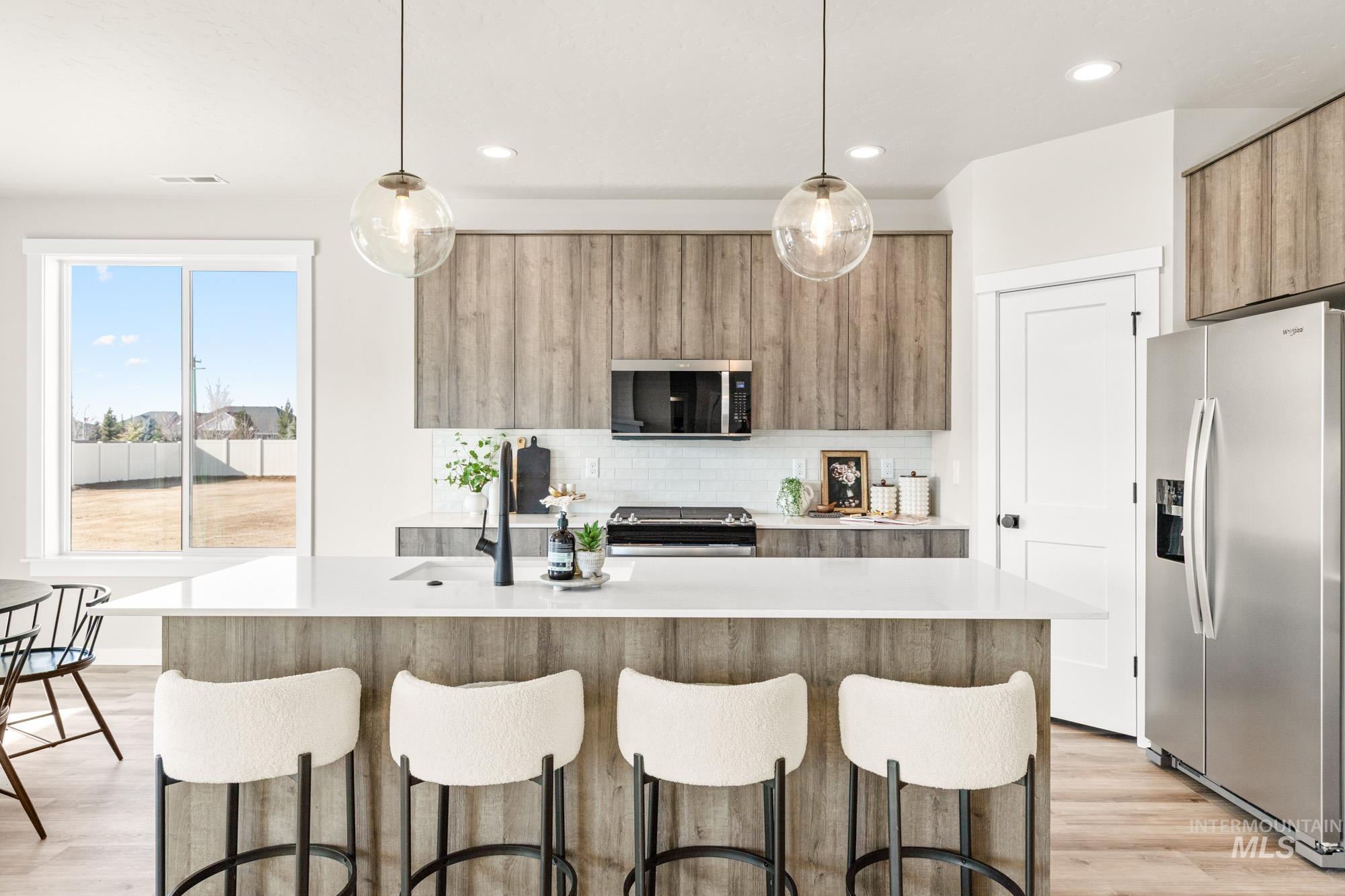5487 West Yarnell Street Eagle, ID 83616 - Photo 11 of 30 Kitchen featuring pendant lighting, stainless steel appliances, modern cabinets, light wood-style floors, and light stone counters