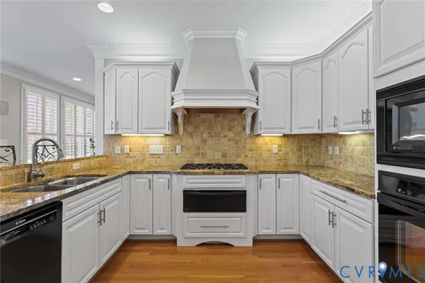 a kitchen with stainless steel appliances granite countertop a stove top oven a sink dishwasher a dining table and chairs with wooden floor