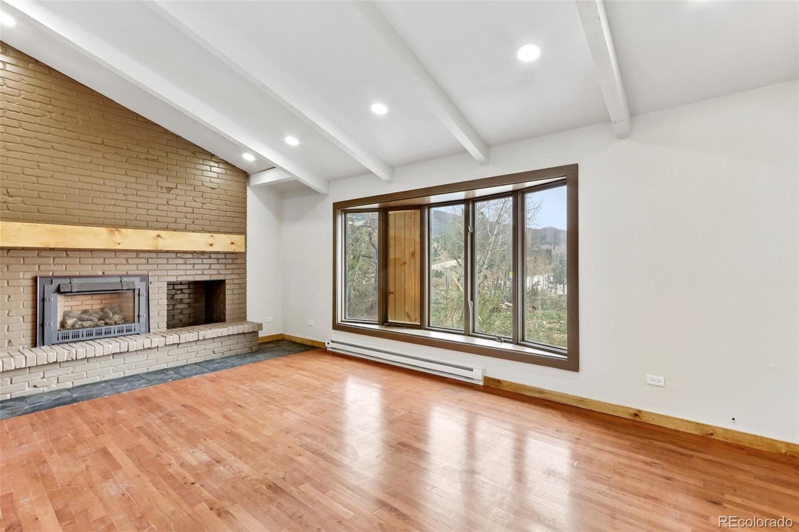 61 Evergreen Road Black Hawk, CO 80422 - Photo 16 of 50 an empty room with floor to ceiling windows and a fireplace