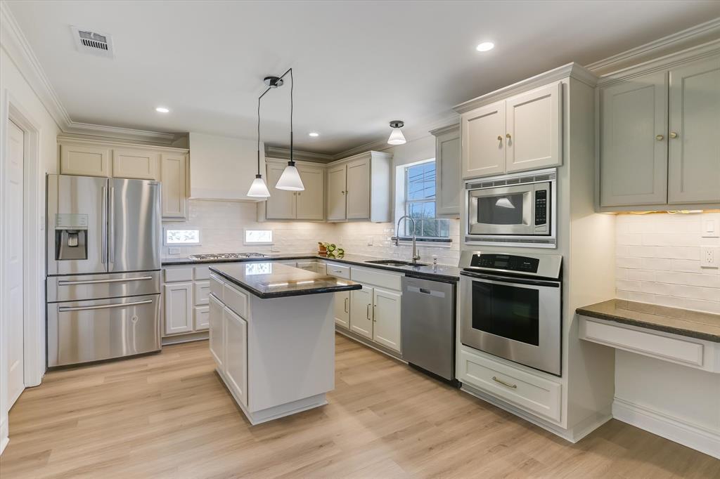 5405 Manor Road Austin, TX 78723 - Photo 3 of 30 Kitchen featuring stainless steel appliances, light wood-style floors, a center island, pendant lighting, and ornamental molding