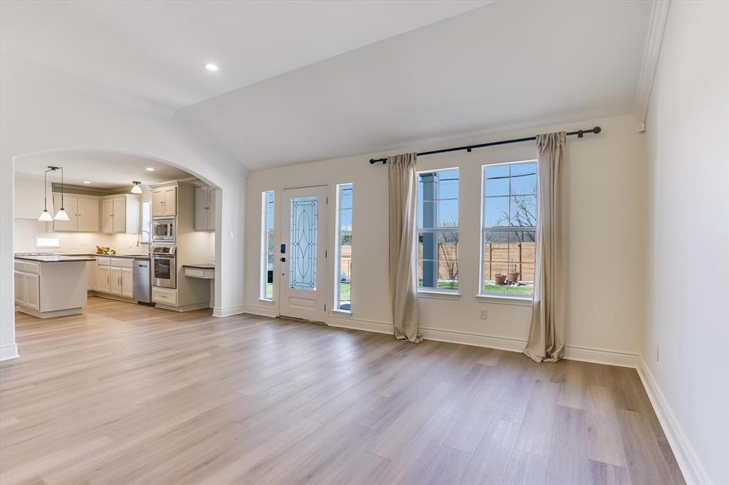 5405 Manor Road Austin, TX 78723 - Photo 4 of 30 Unfurnished living room featuring arched walkways, vaulted ceiling, light wood-style flooring, and recessed lighting