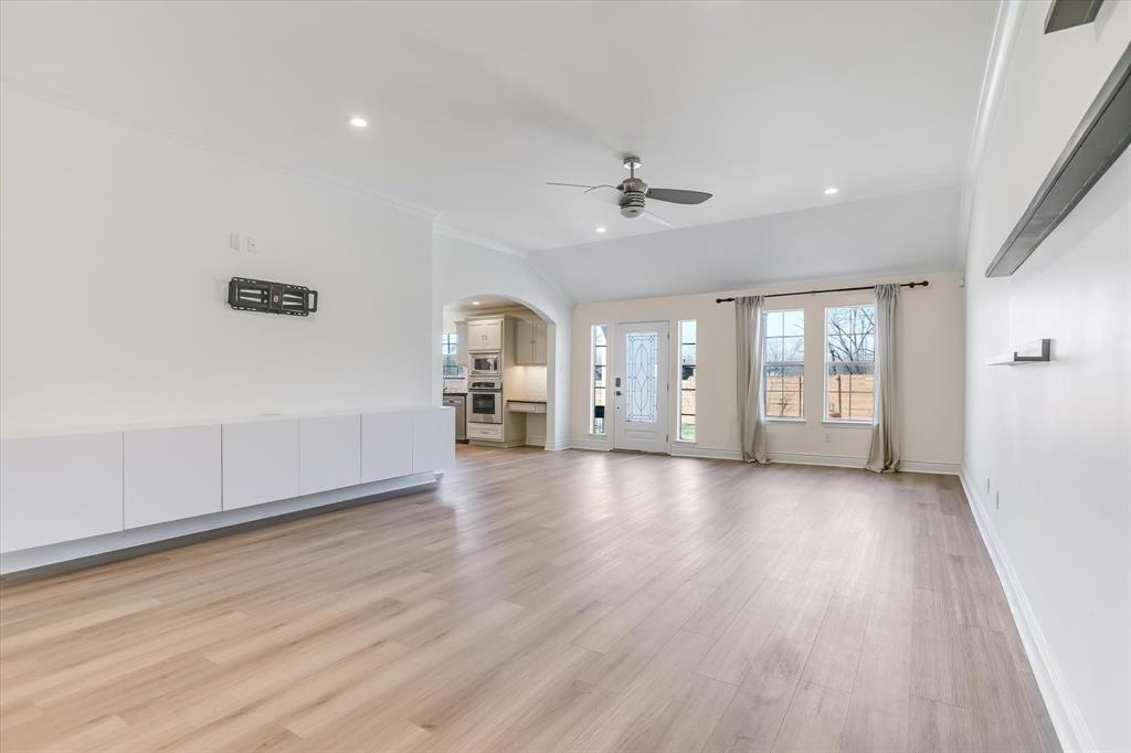 5405 Manor Road Austin, TX 78723 - Photo 7 of 30 Unfurnished living room featuring arched walkways, light wood-style flooring, lofted ceiling, ceiling fan, and recessed lighting