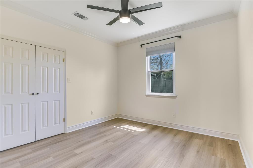 5405 Manor Road Austin, TX 78723 - Photo 10 of 30 Unfurnished bedroom featuring crown molding, light wood-style floors, a ceiling fan, and a closet