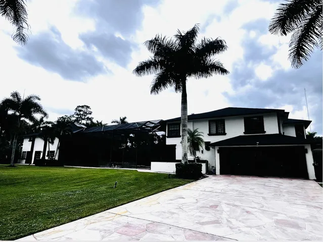 a front view of a house with a garden and trees