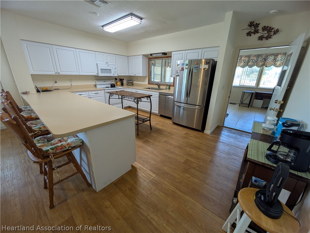2701 Brunns Road Sebring, FL 33872 - Photo 3 of 29 a kitchen with a refrigerator a stove top oven a sink dishwasher and white cabinets with wooden floor