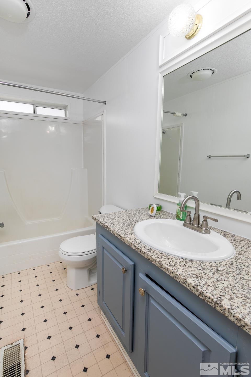 5215 Workman Road Fallon, NV 89406 - Photo 14 of 21 a bathroom with a granite countertop sink a toilet a mirror and shower