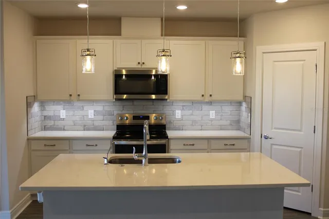a kitchen with kitchen island a stove a sink and a microwave
