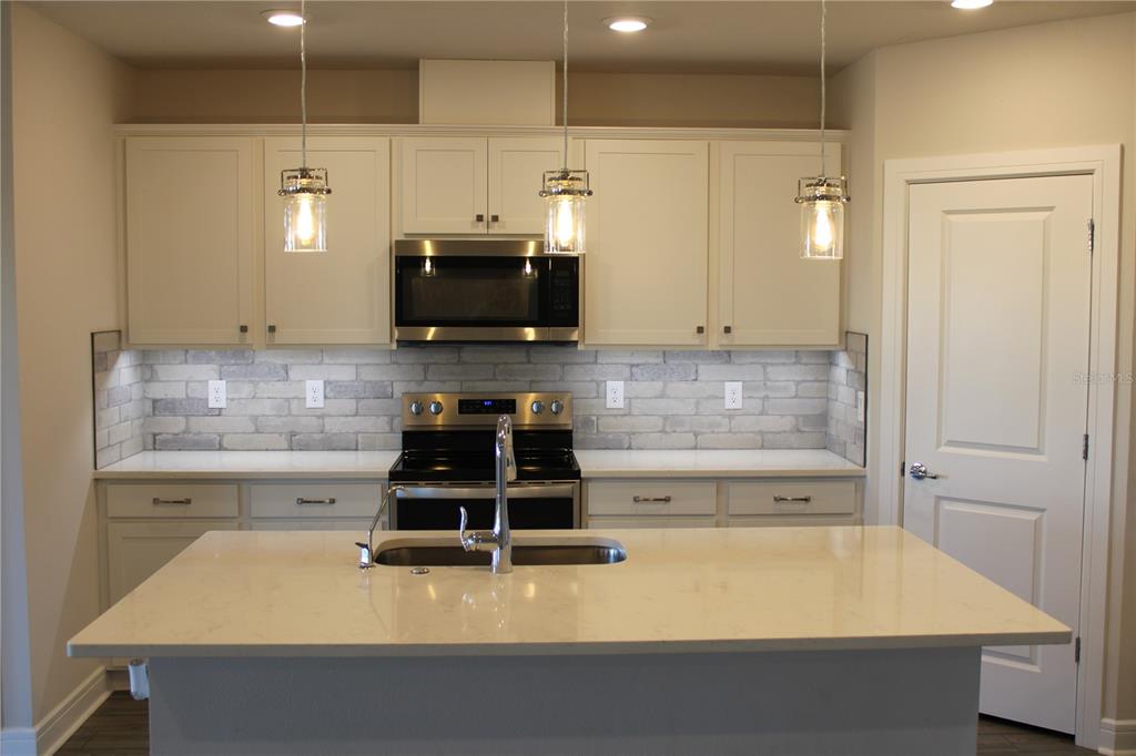8232 Reefbay Cove Parrish, FL 34221 - Photo 4 of 64 a kitchen with kitchen island a stove a sink and a microwave