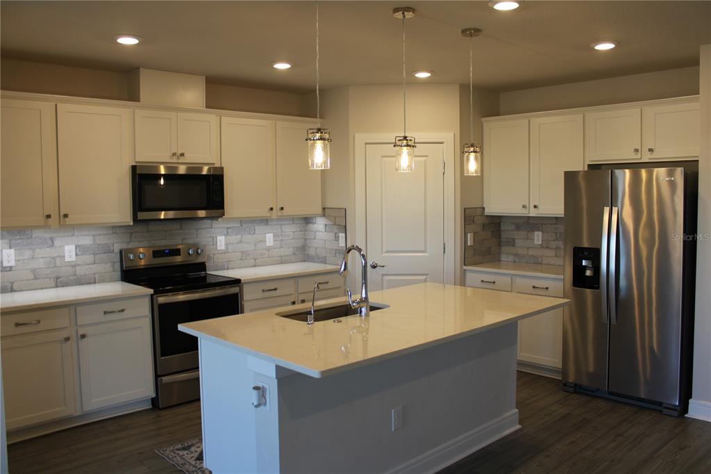 8232 Reefbay Cove Parrish, FL 34221 - Photo 5 of 64 a kitchen with kitchen island a sink stainless steel appliances and cabinets
