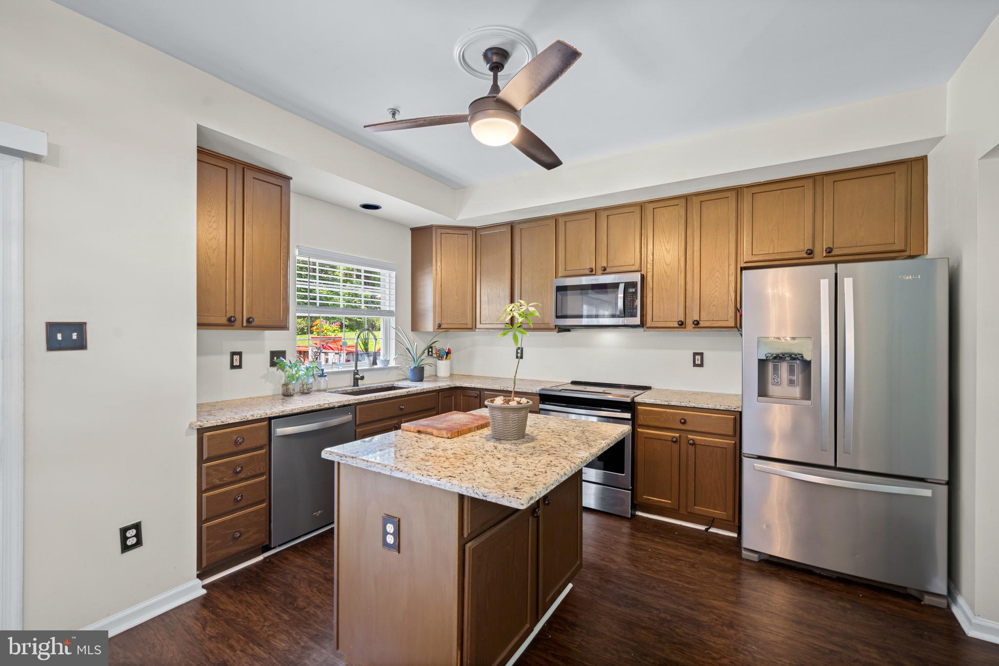 9837 Sherwood Farm Road Owings Mills, MD 21117 - Photo 9 of 35 a kitchen with wooden cabinets a sink a stove a refrigerator and a refrigerator