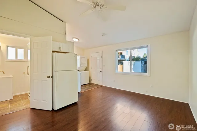 a view of a kitchen with wooden floor a ceiling fan and windows