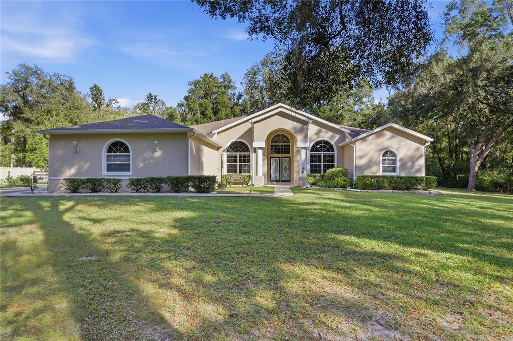 4060 South Kenvera Loop Inverness, FL 34450 - Photo 2 of 50 a front view of a house with a garden and trees