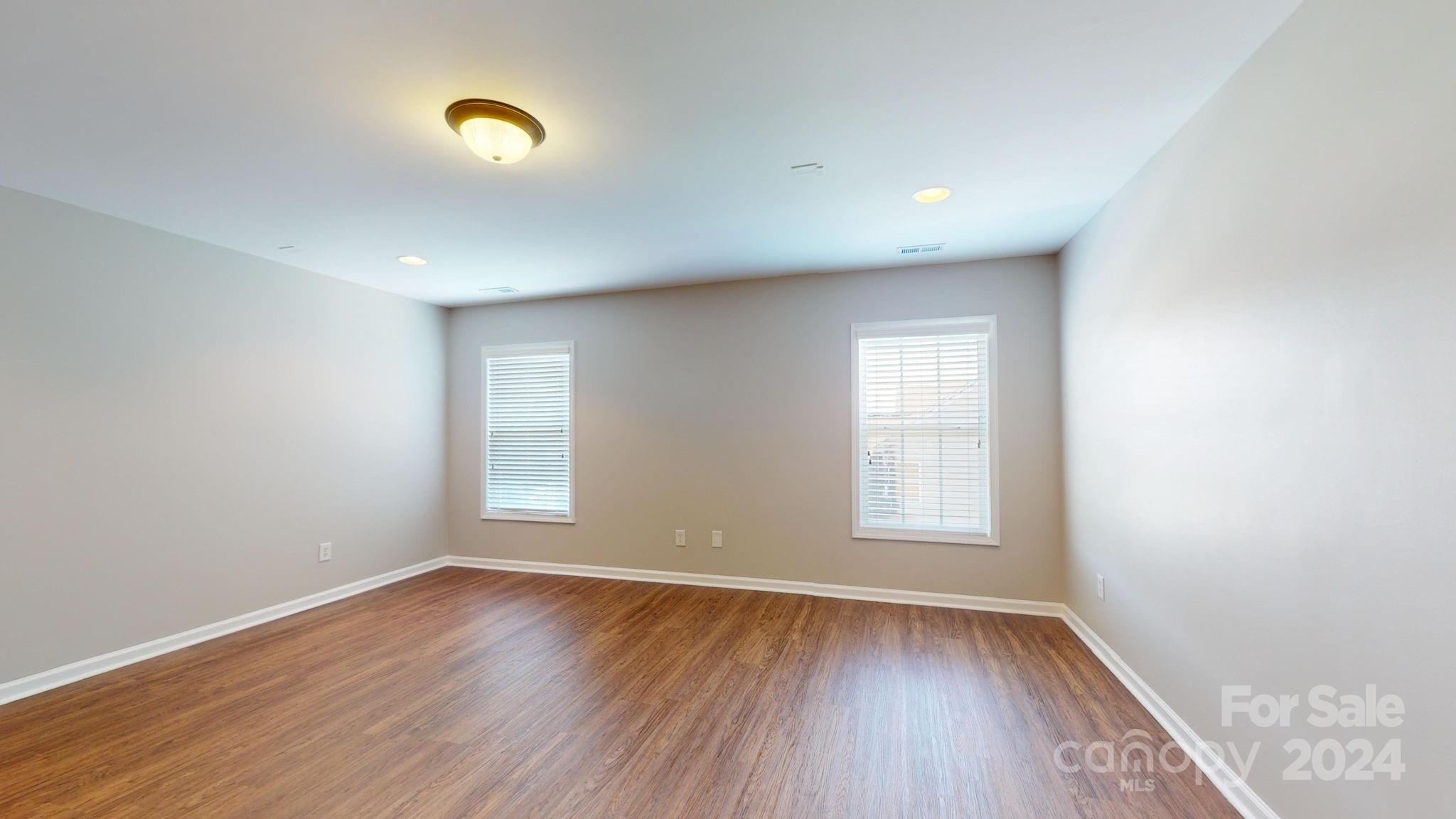 8386 Burgundy Ridge Drive Harrisburg, NC 28075 - Photo 19 of 44 an empty room with wooden floor and windows