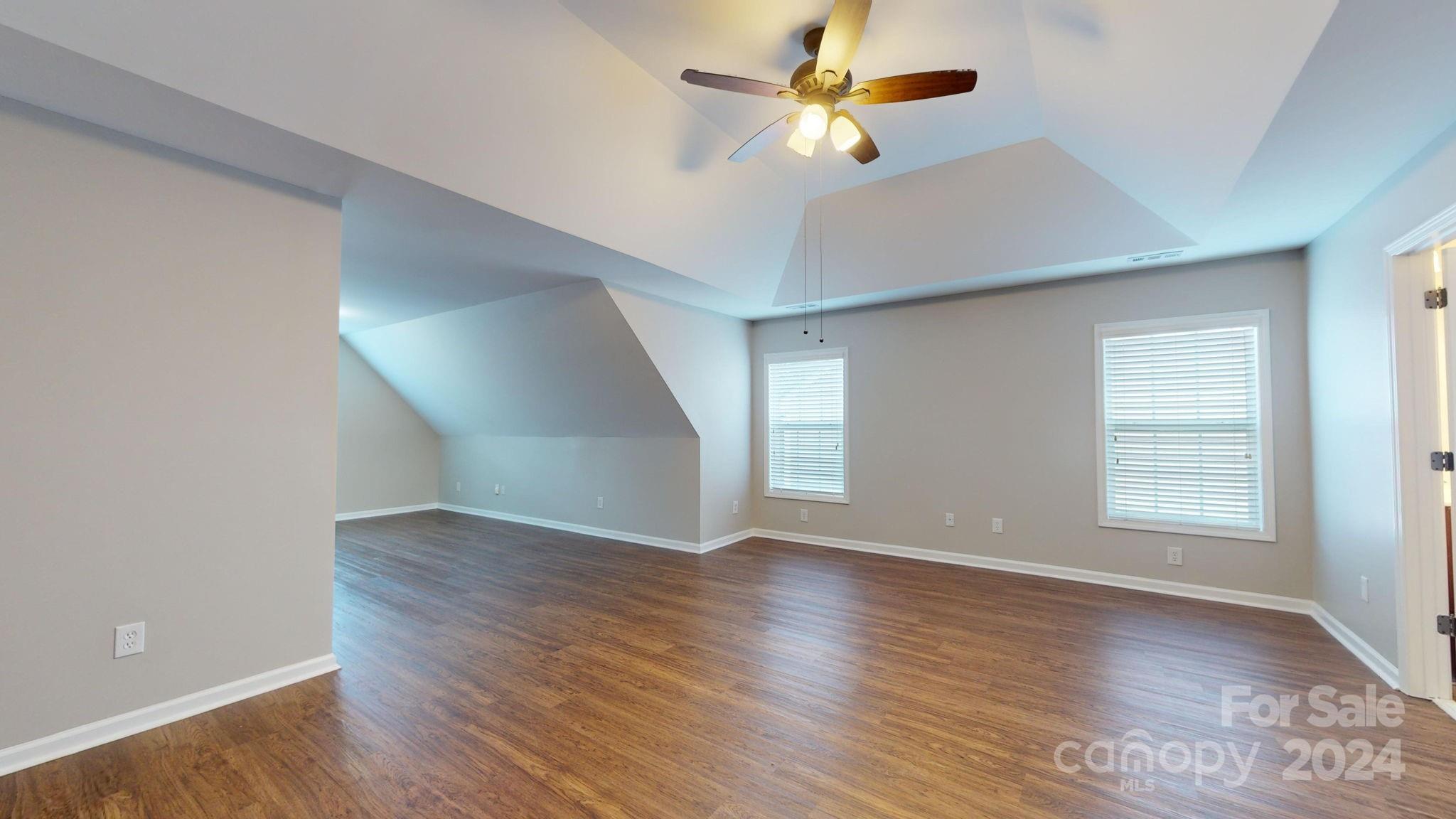 8386 Burgundy Ridge Drive Harrisburg, NC 28075 - Photo 22 of 44 an empty room with wooden floor fan and windows